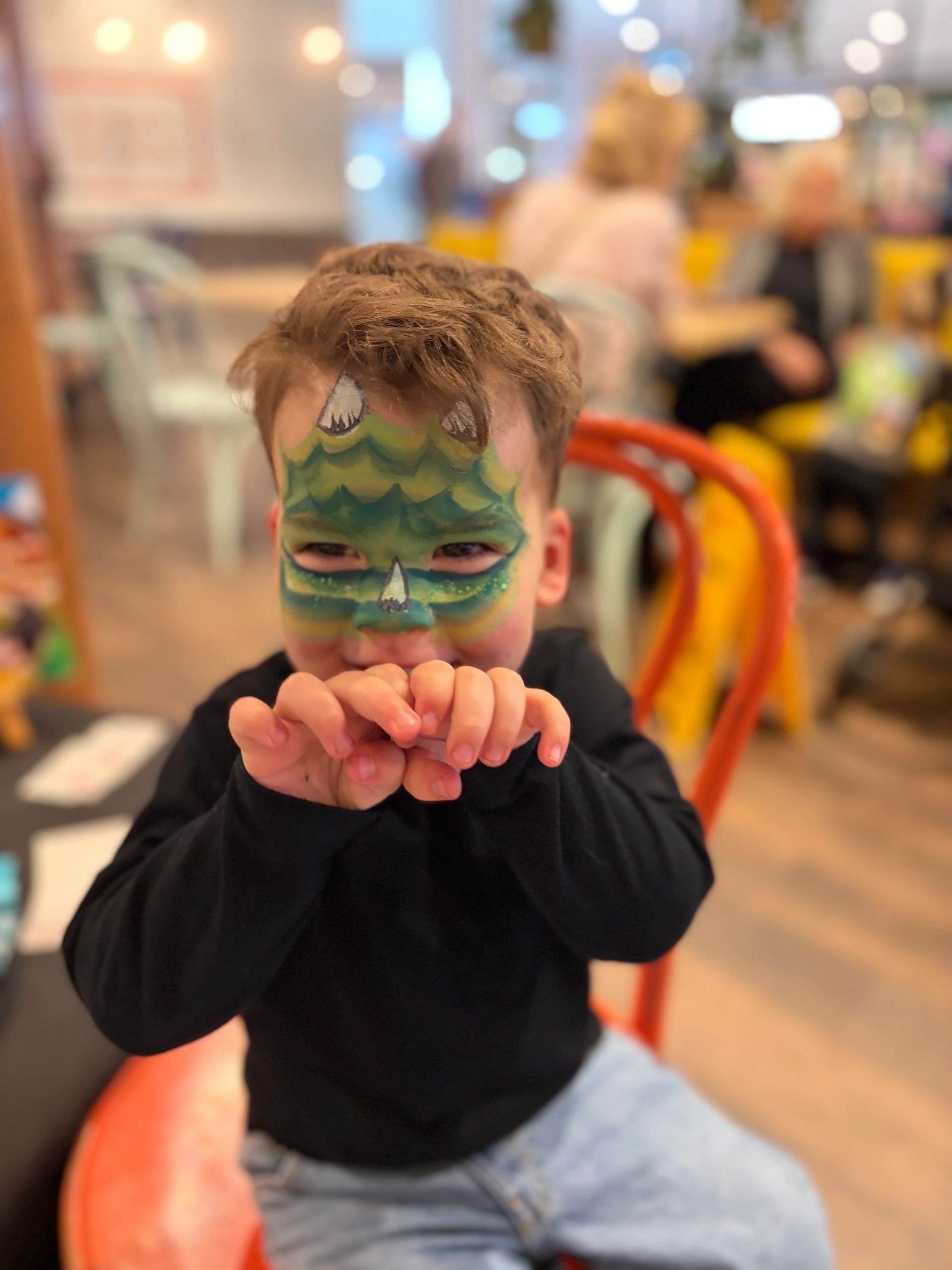 Child with green dinosaur face paint