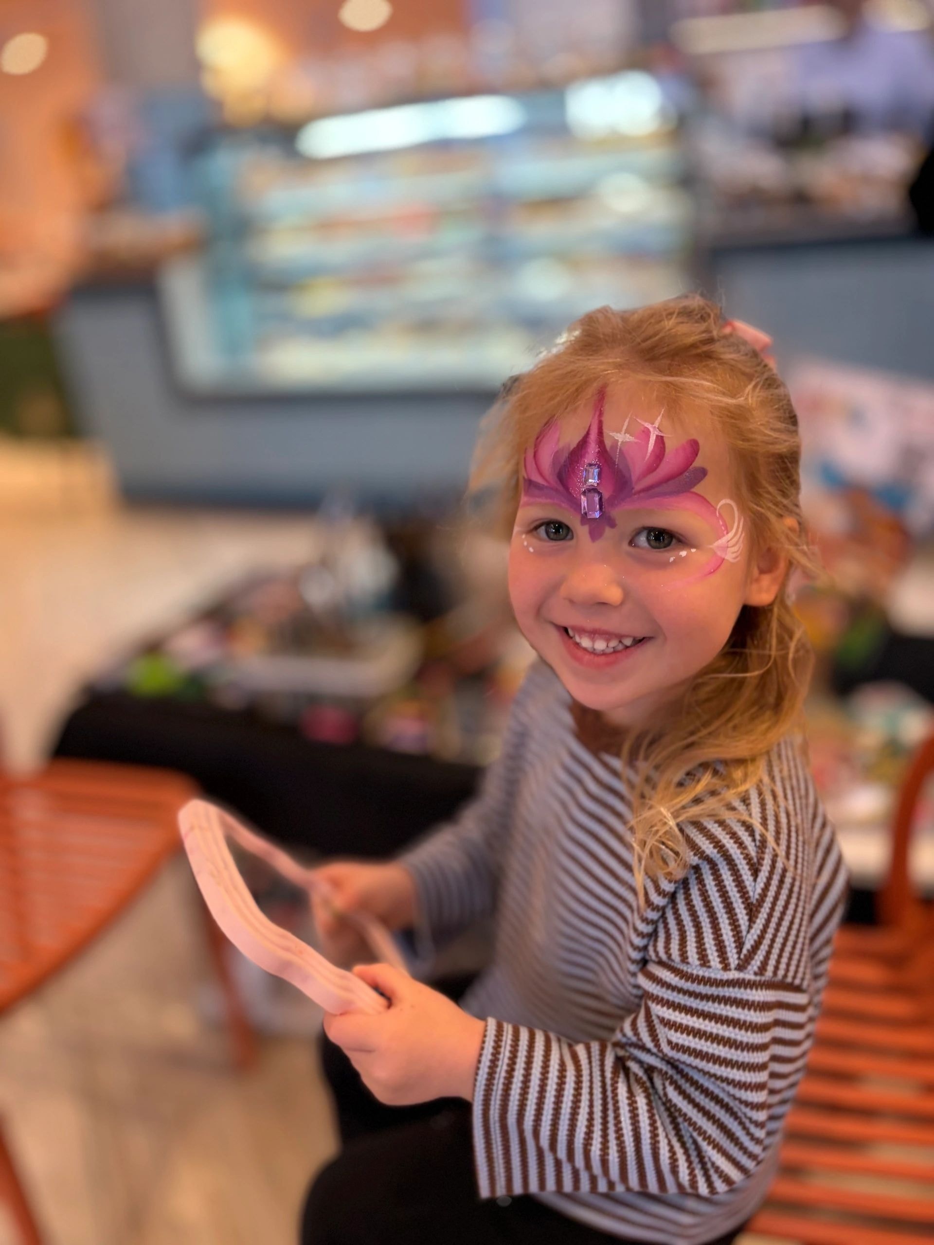 Child with pink and purple lotus face paint