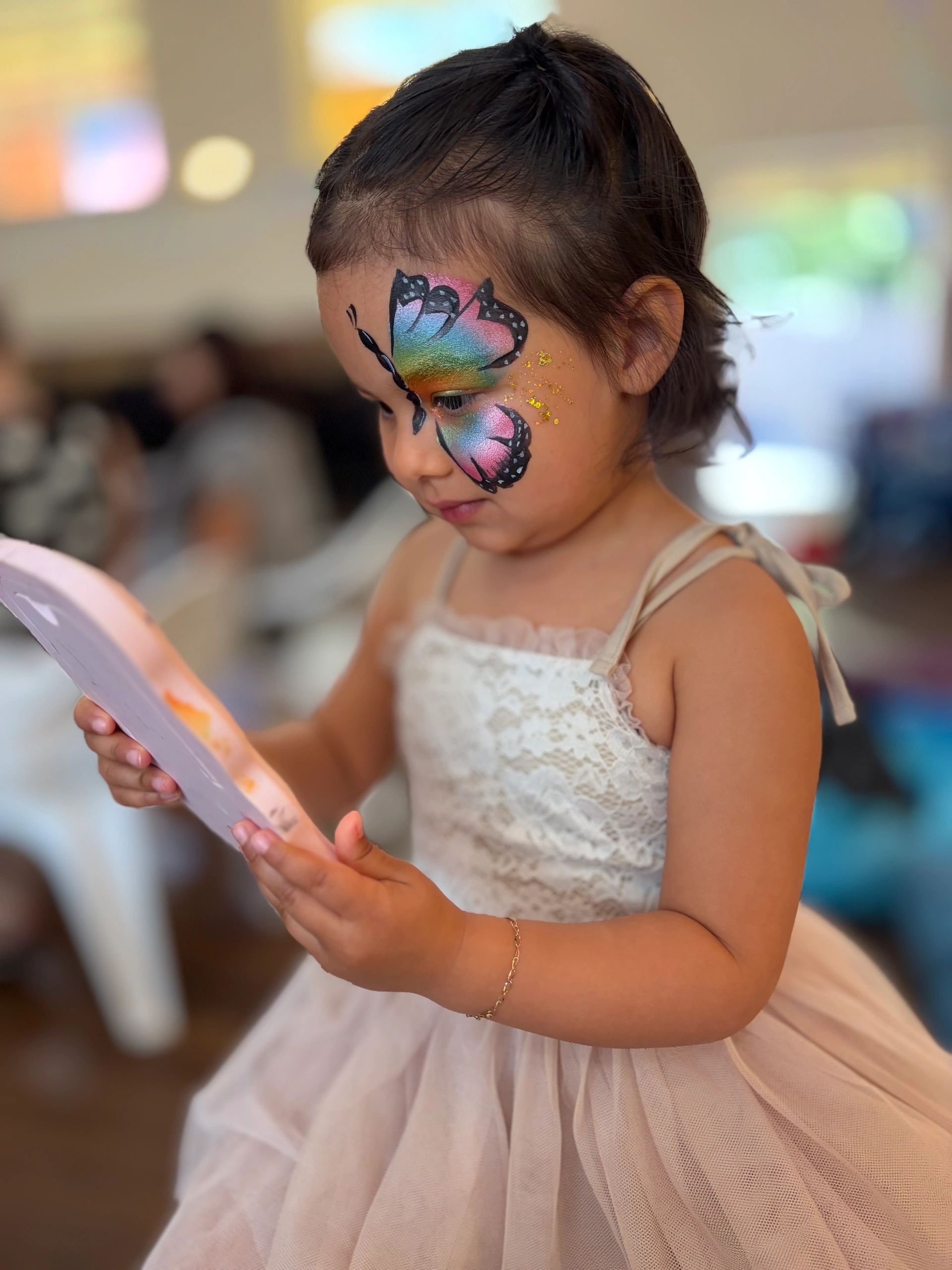 Child with rainbow butterfly glitter face paint