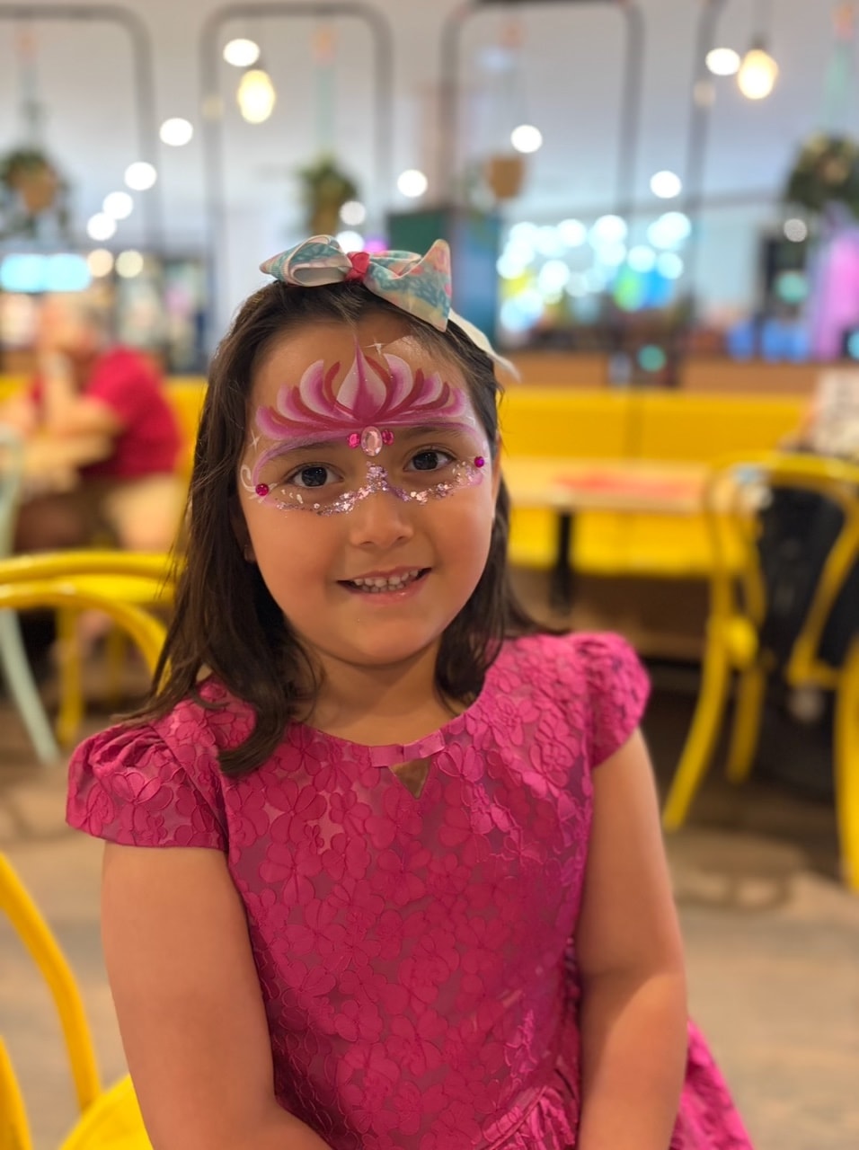 Child with rainbow butterfly face paint in unicorn shirt