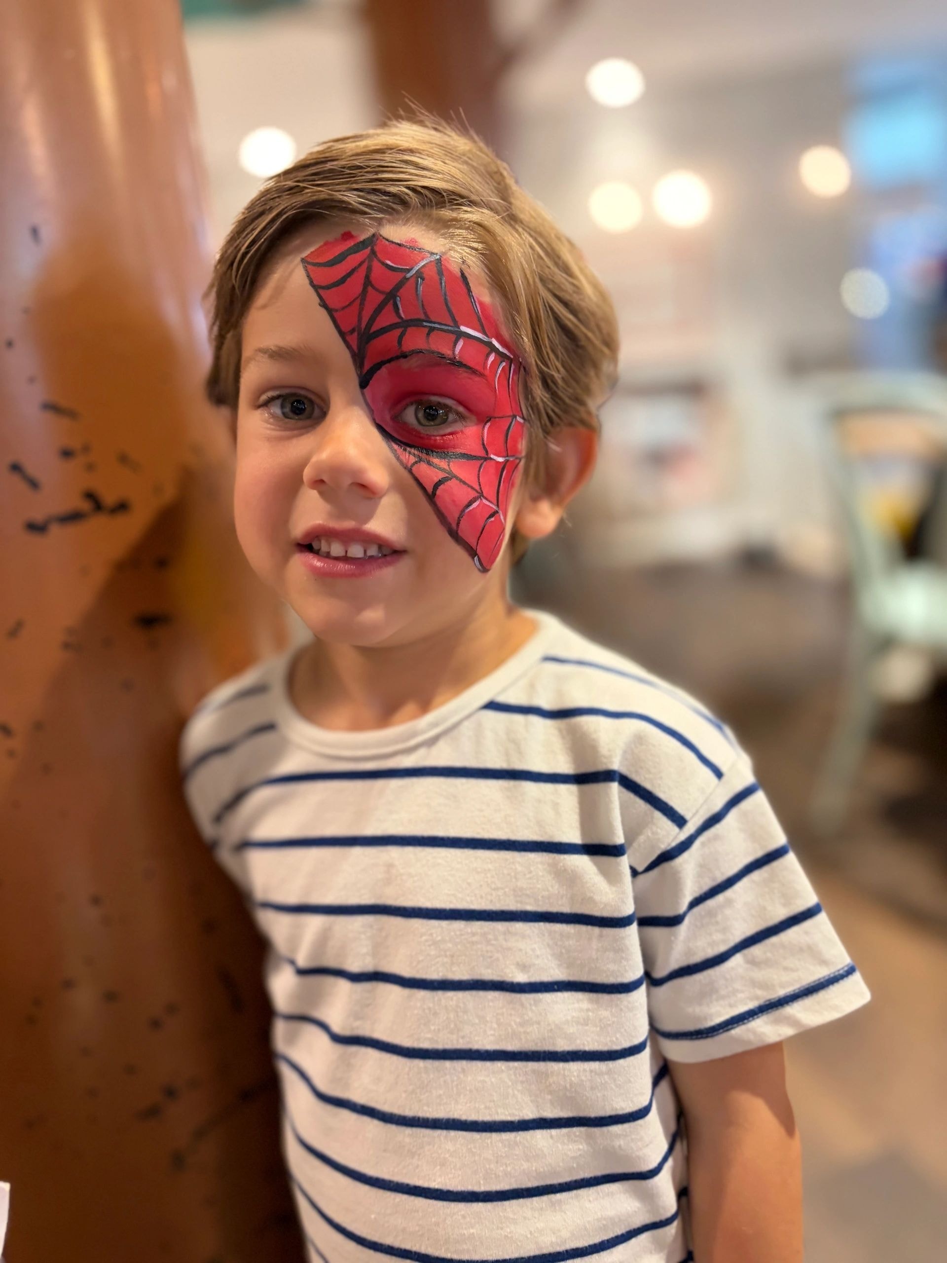 Child with spider web half-face paint smiling