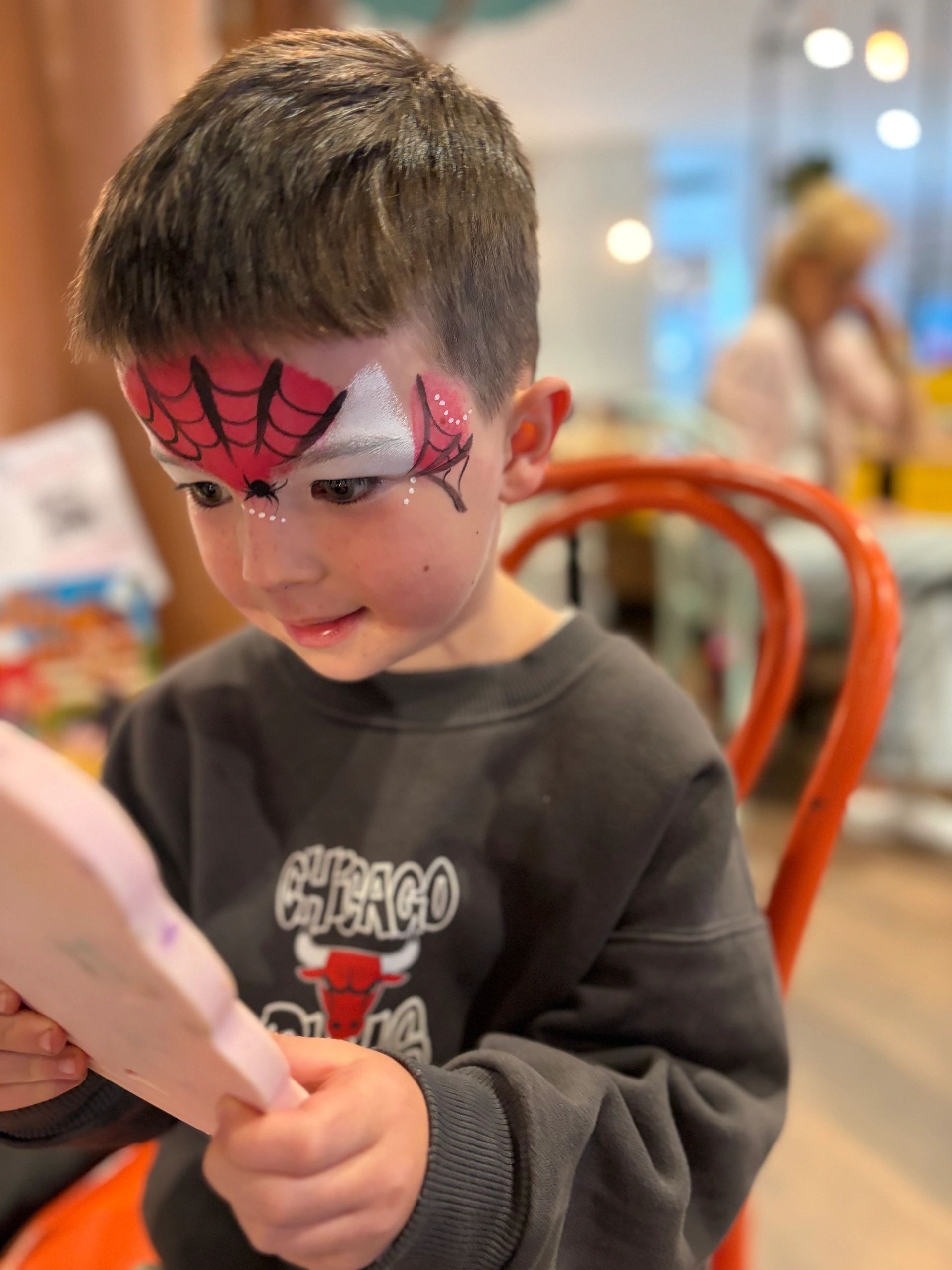 Child with red and black spider web face paint