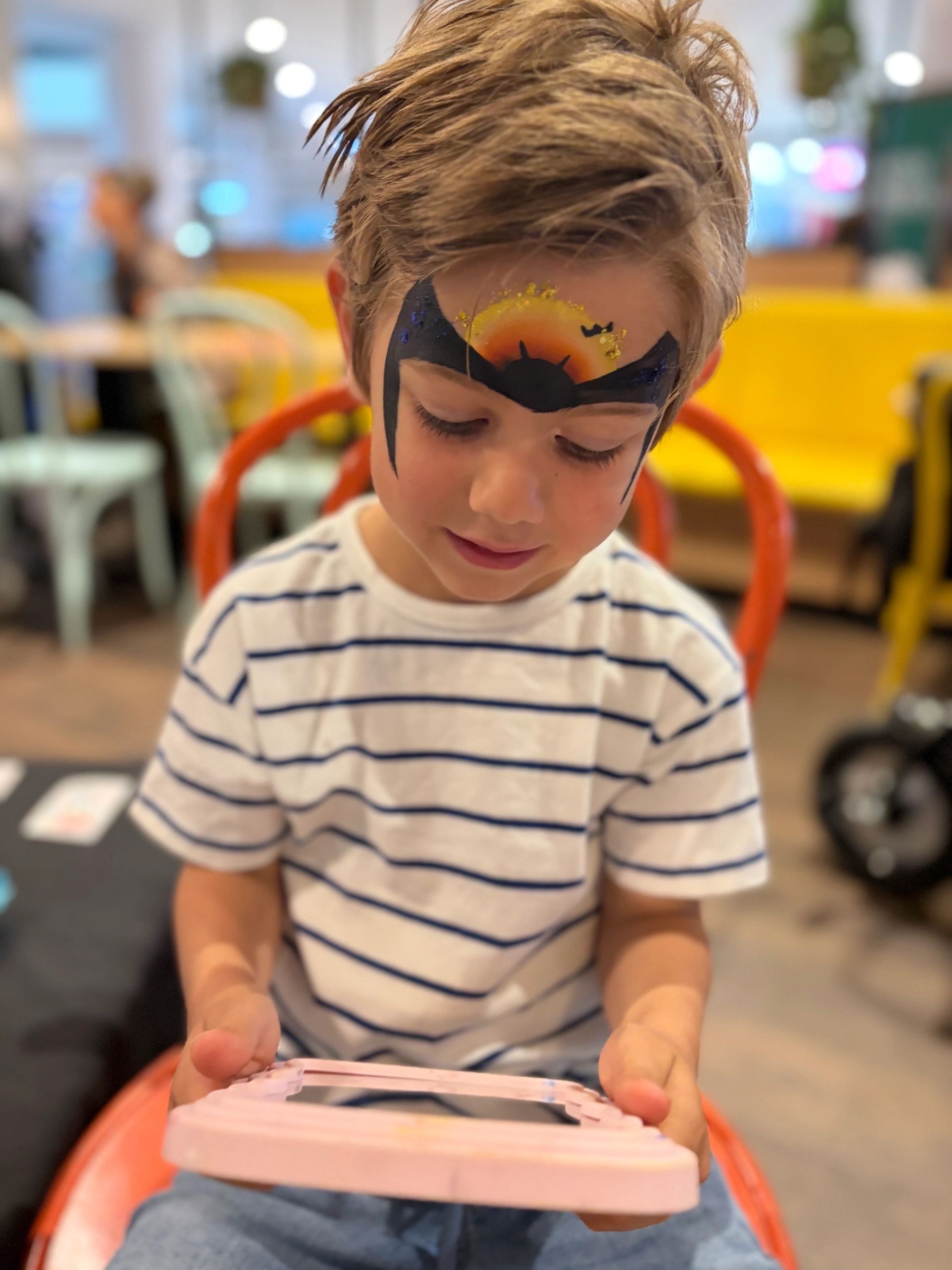 Child with sunset and bats face paint design